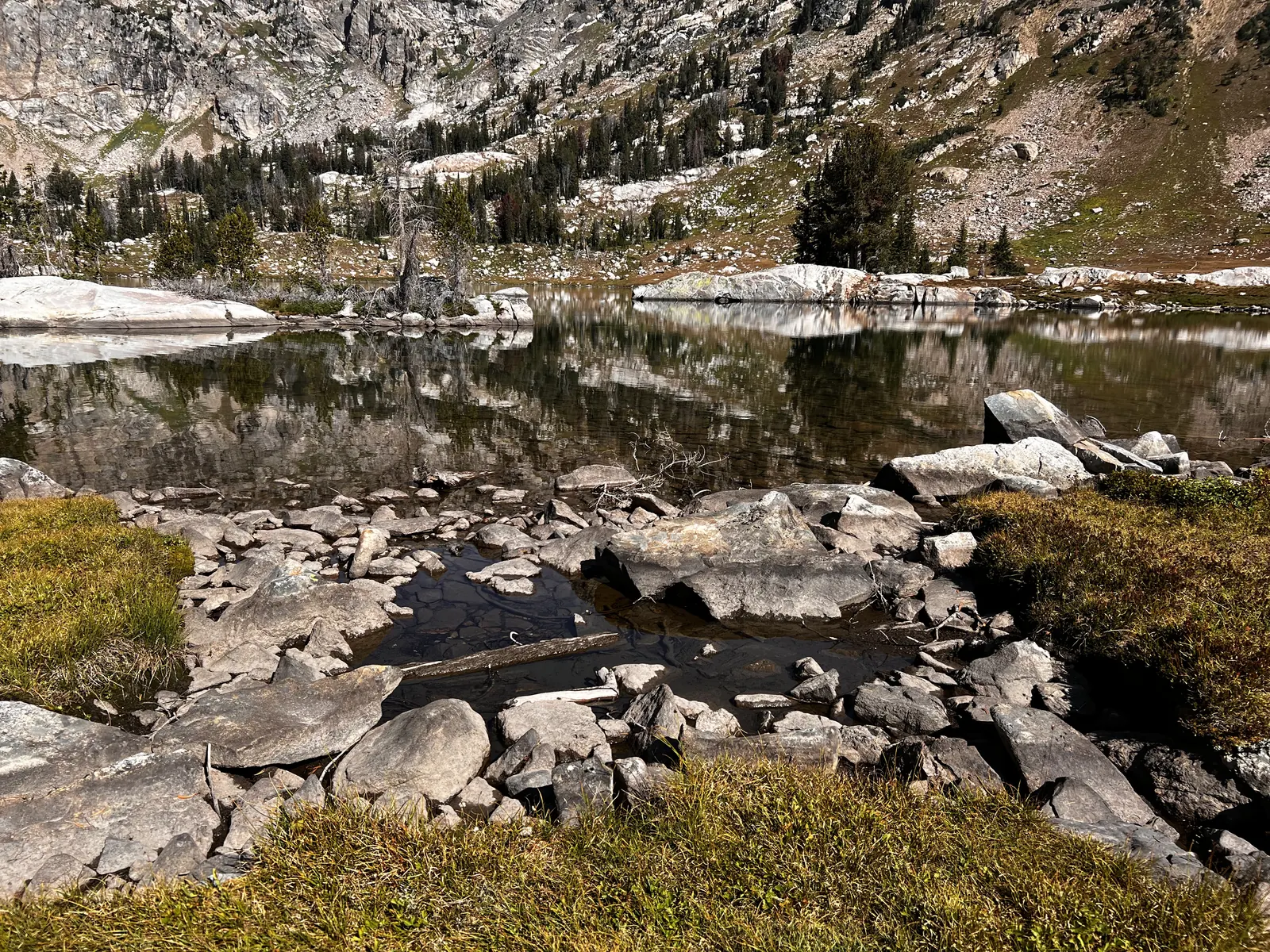 Still alpine lake surrounded by granite boulders