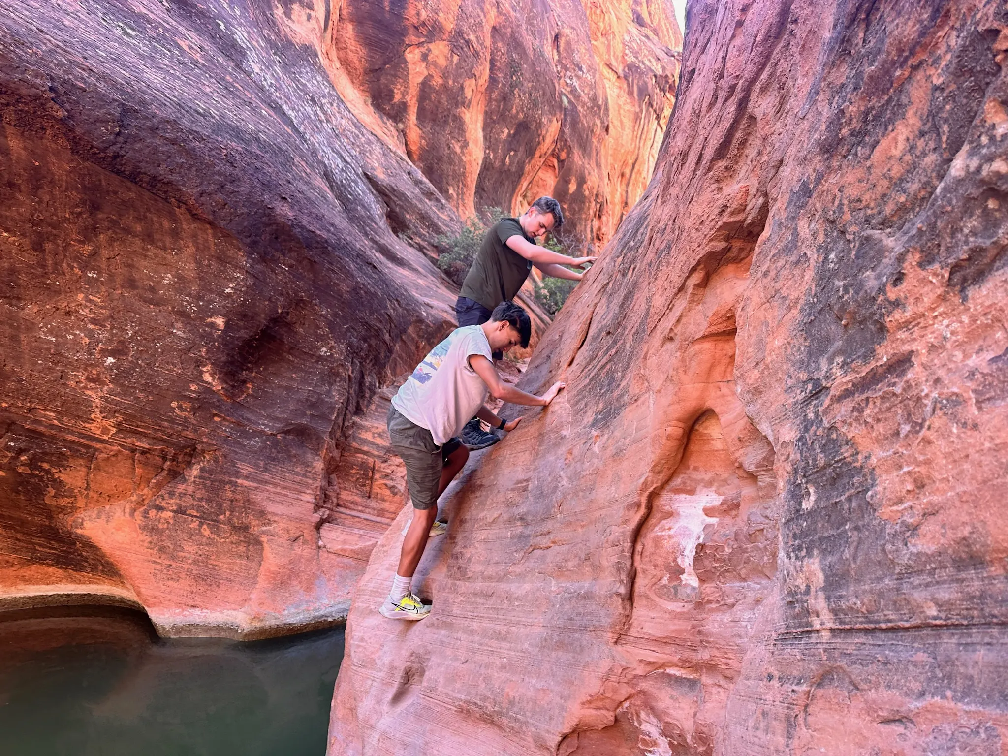 Charles, in a light shirt, making his way through a red-rock canyon with a companion above him