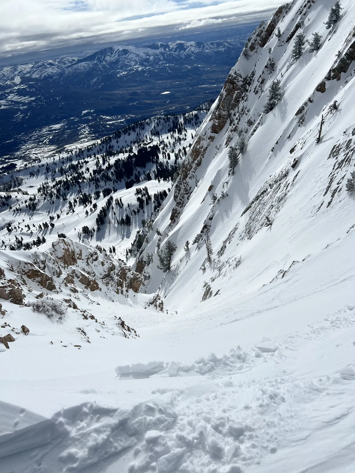 Looking down a steep, snowy bowl toward the valley