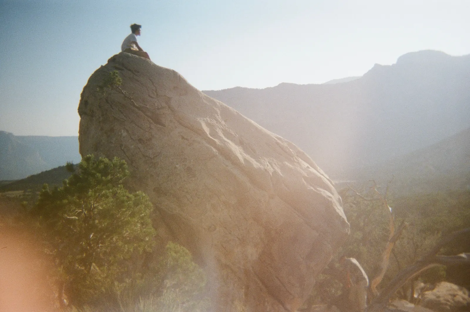 Sitting on top of a huge boulder above a hazy mountain valley